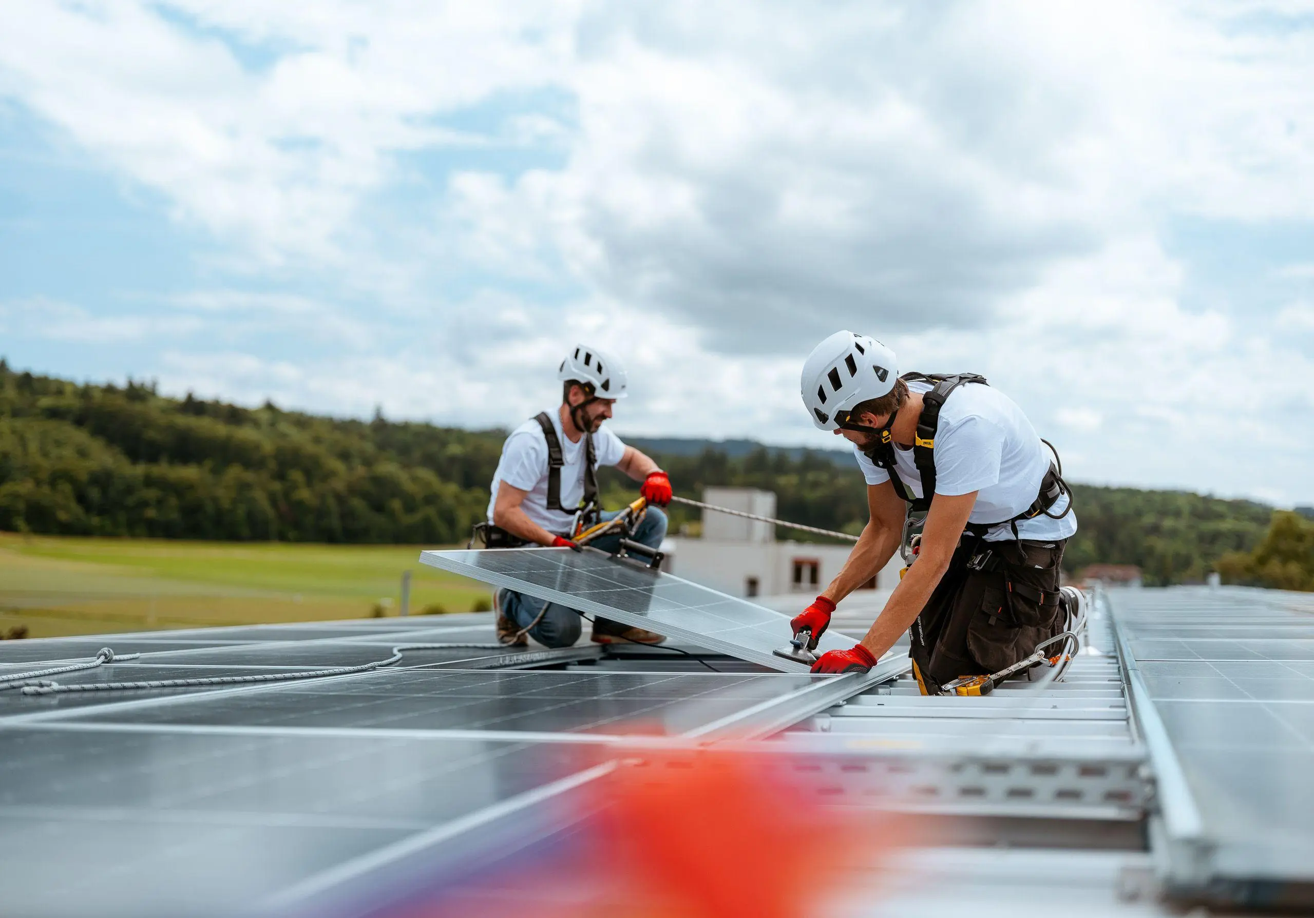 Zwei Arbeiter installieren ein Solarpanel auf einem Dach
