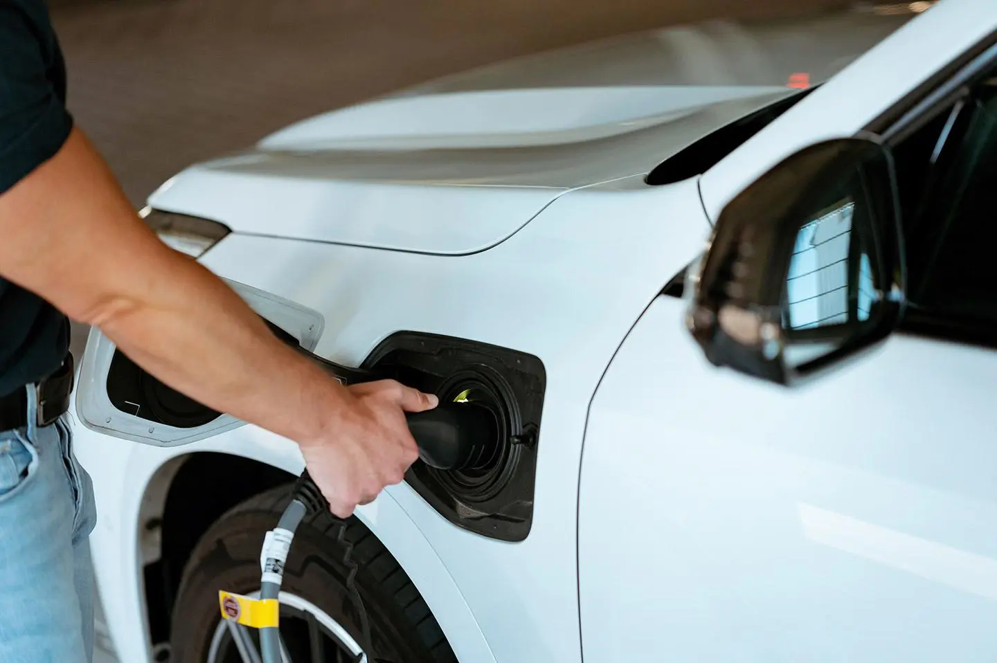 Elektroauto lädt mit Solarstrom an Wallbox vor einem Haus mit Solaranlage und Wärmepumpe