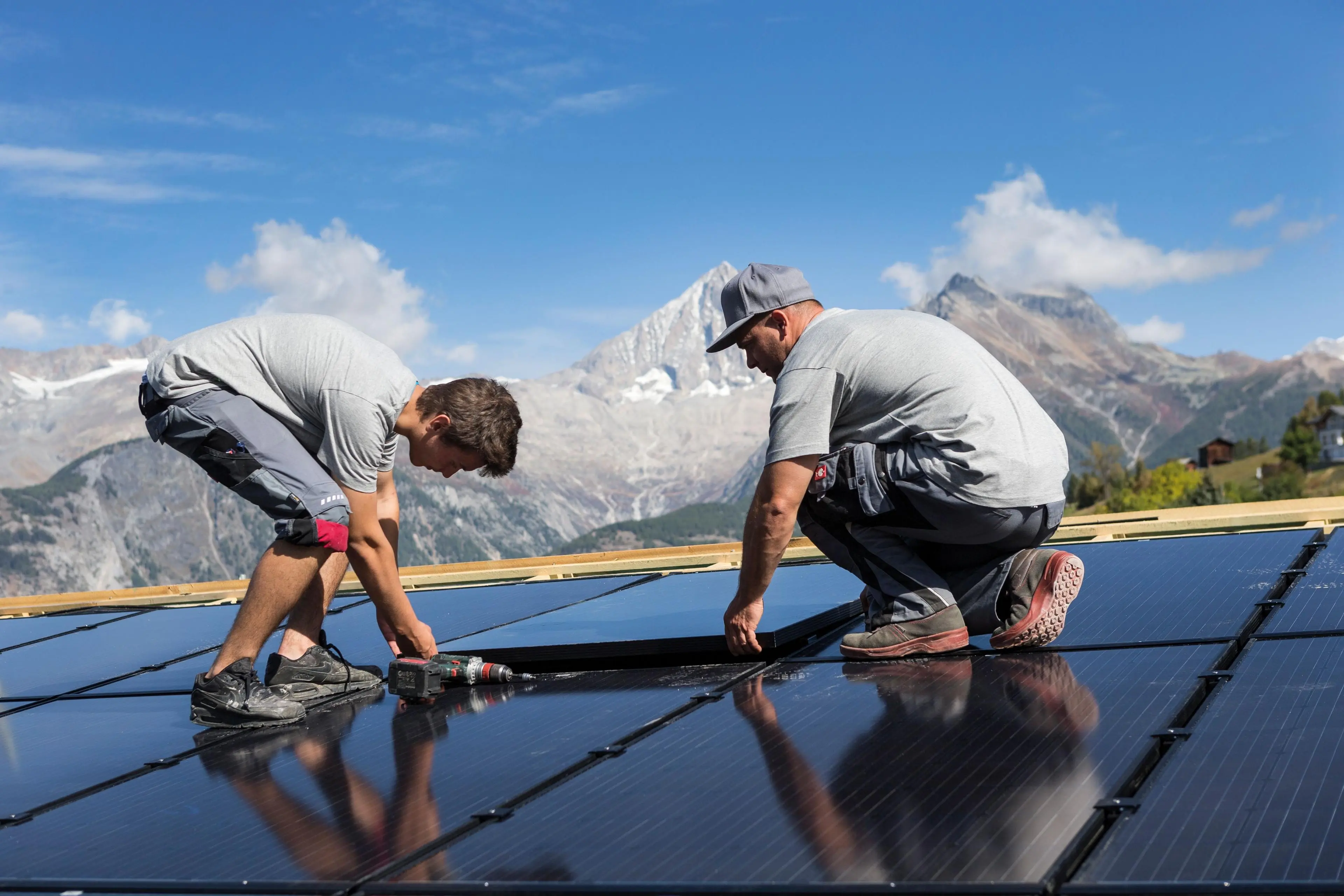 Deux installateurs montent des panneaux solaires sur un toit