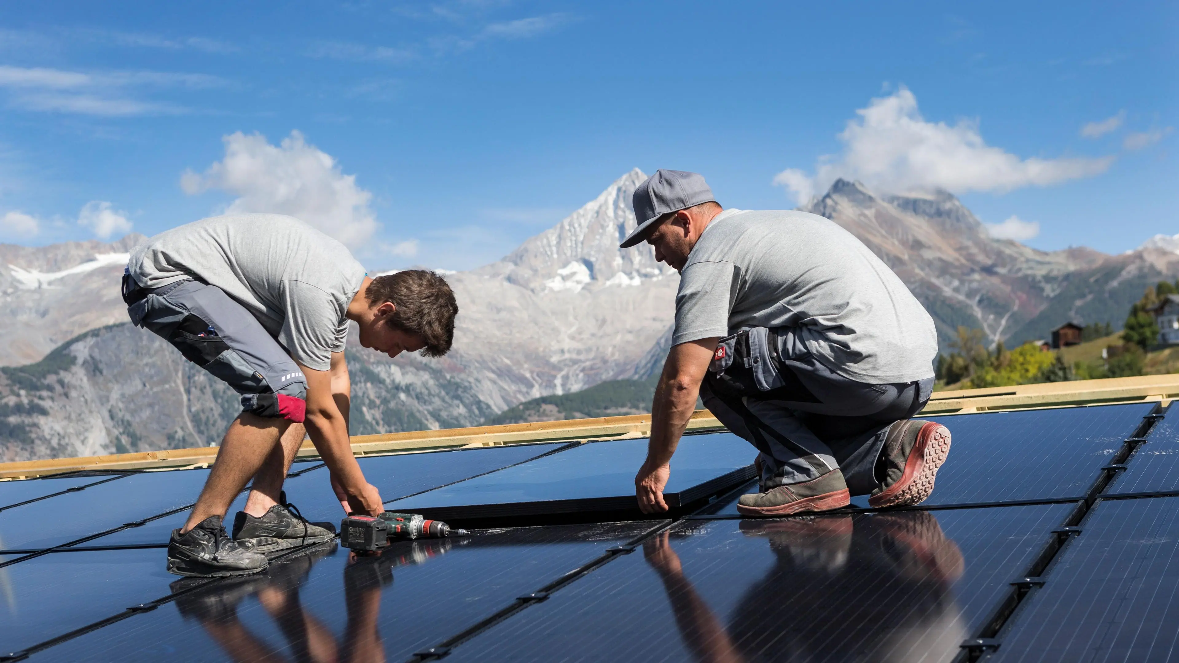 Zwei Installateure montieren Solarpanels auf einem Dach