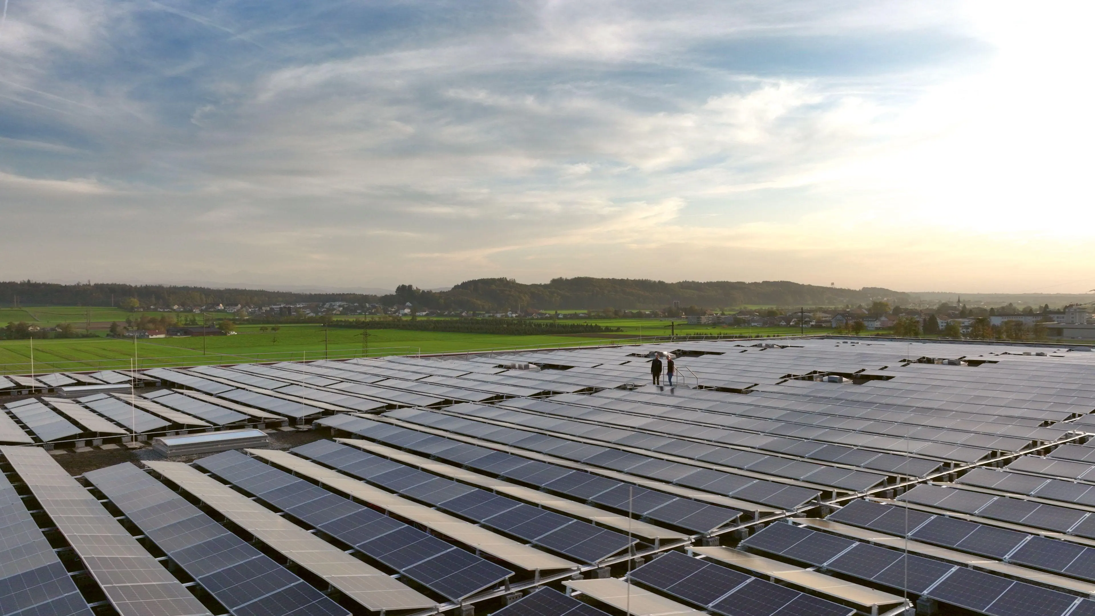 Zwei Arbeiter stehen auf einem grossen Dach mit Solarpanels