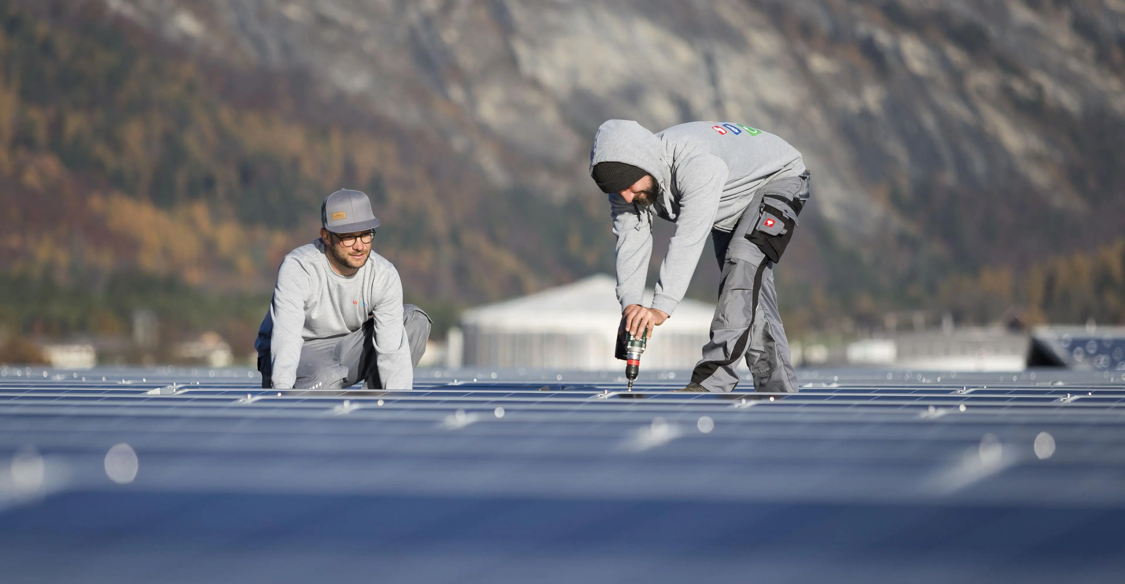 Deux ouvriers installent un système photovoltaïque sur la façade d'un immeuble