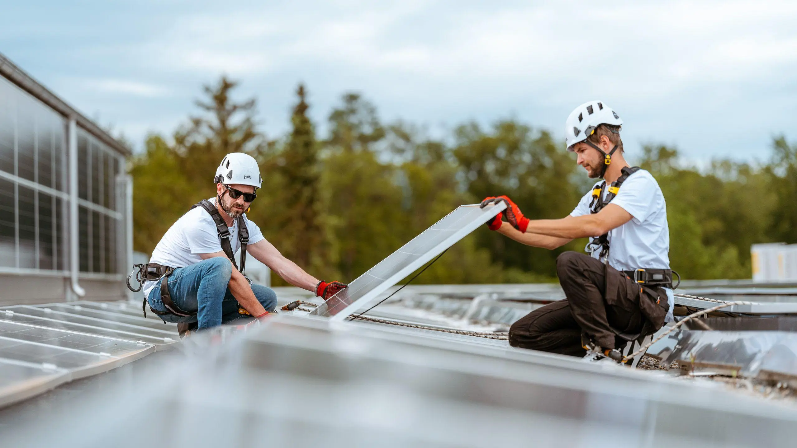 Zwei Installateure montieren Solarpanels auf einem Dach